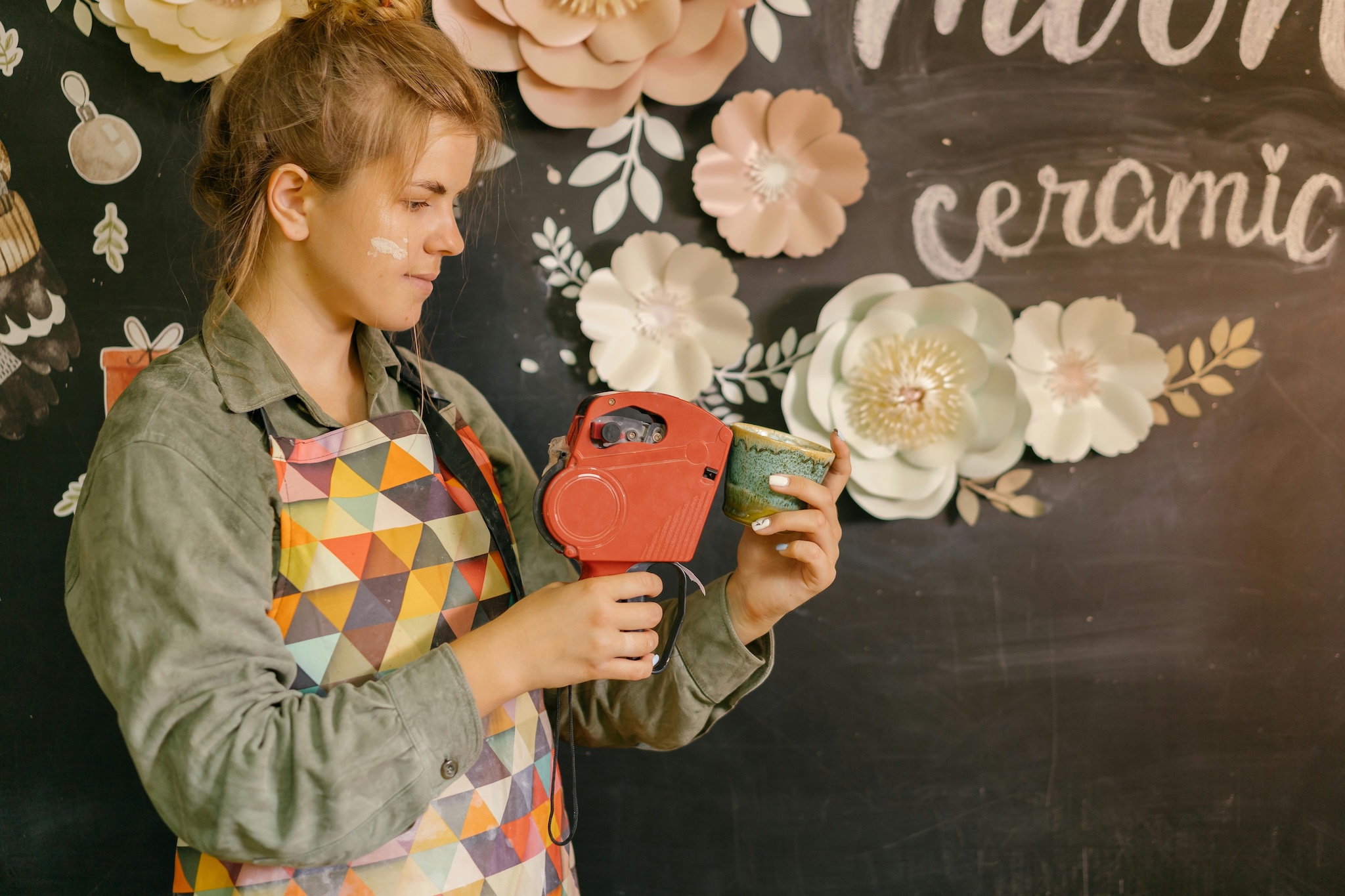Woman in apron labeling handmade cup with a label maker