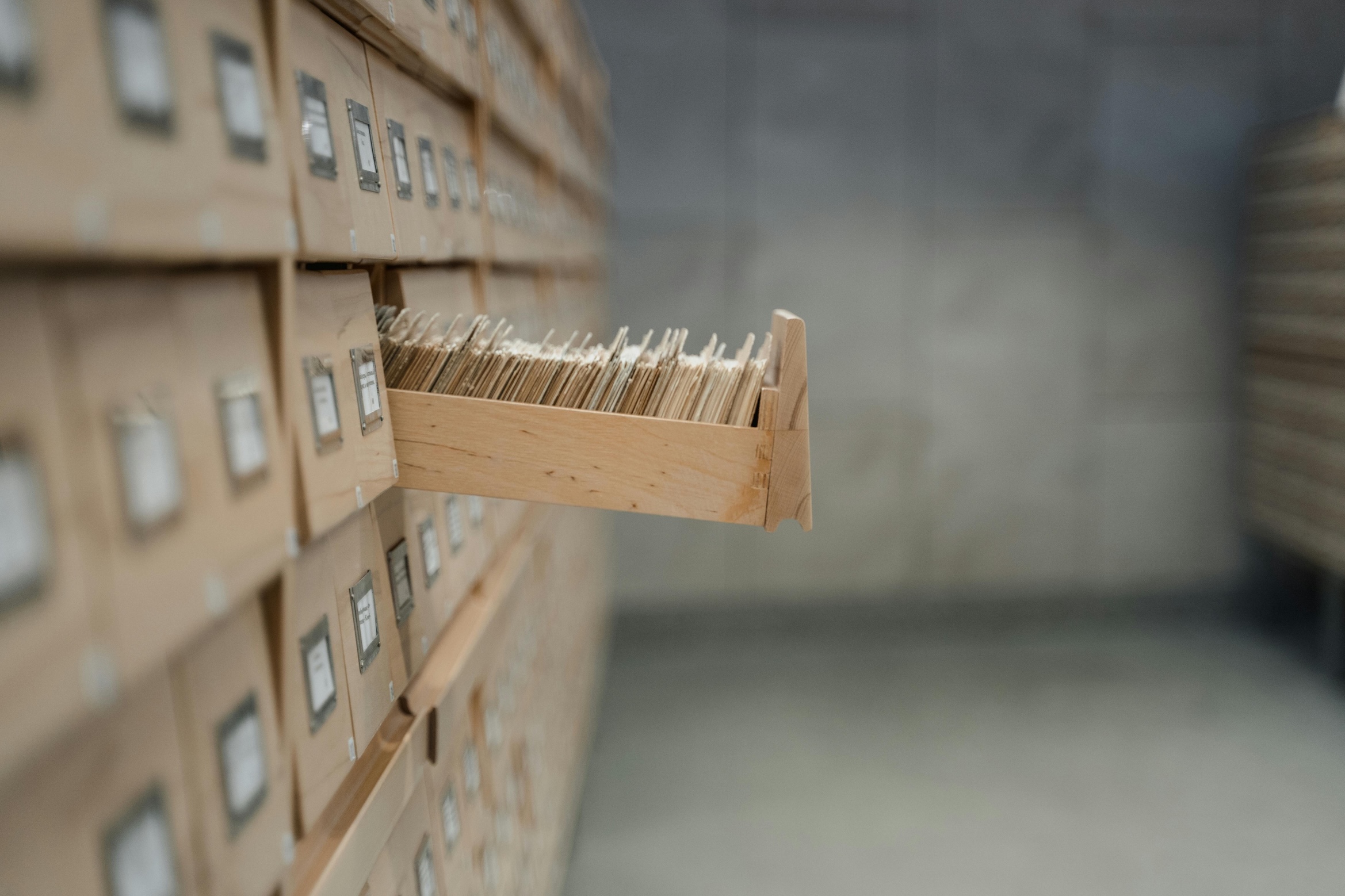 A library filing cabinet with one open drawer containing index cards